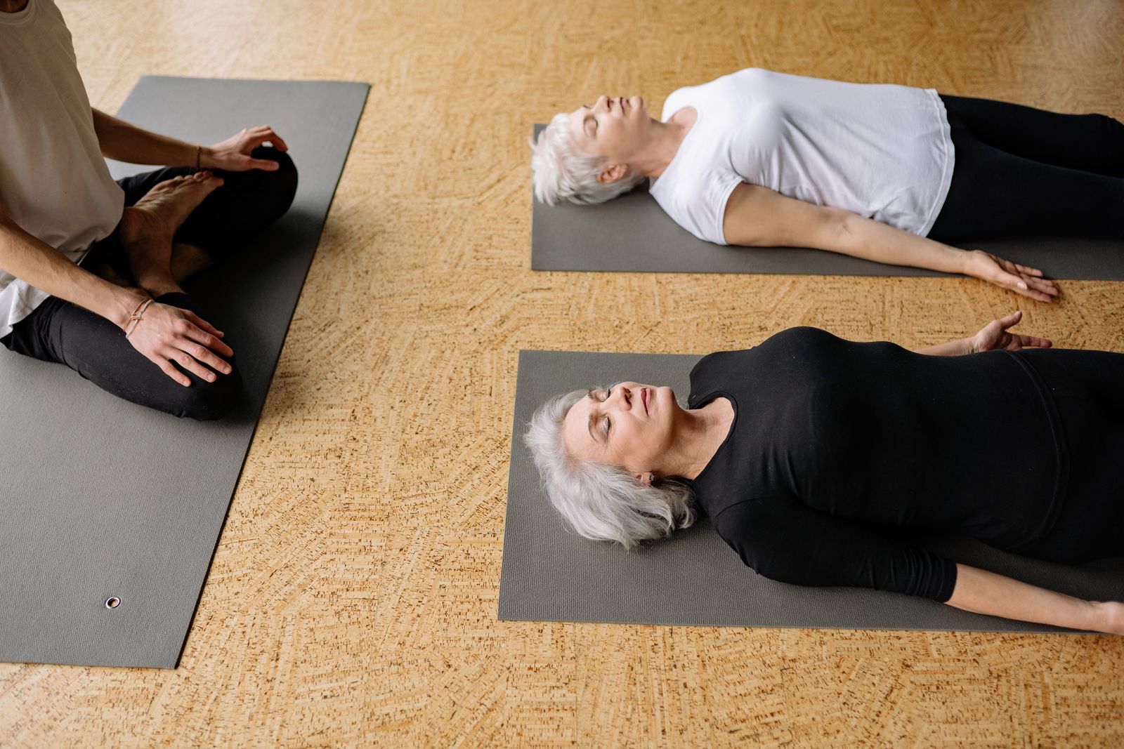 A facilitator sitting beside people lying on mats during a small-group breathwork session